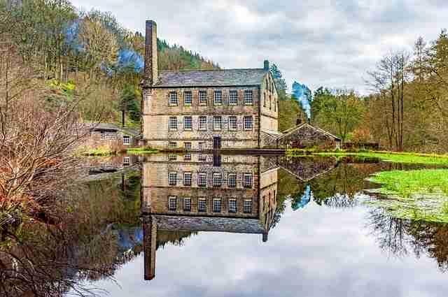 Gibson mill in hardcastle crags on a summers day with the mill being reflected in the river.
